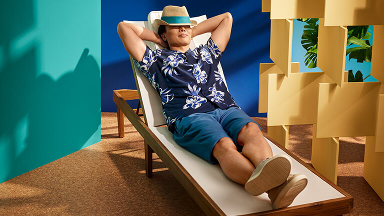 Leisure traveller wearing a fedora, lounging on a beach chair.