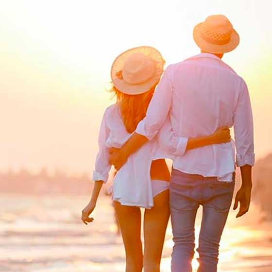 Couple walking with arms around each other on beach