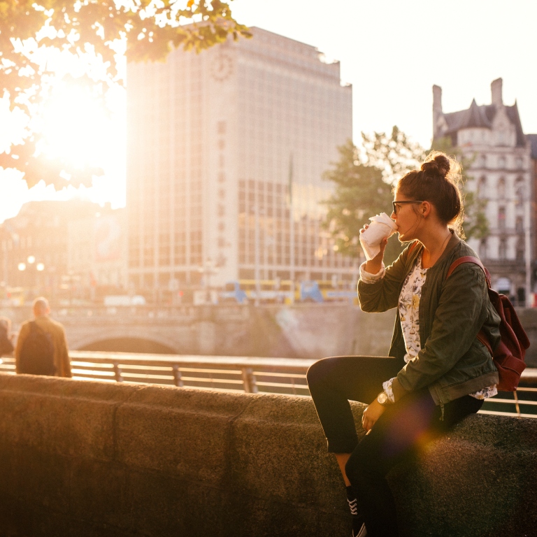 Woman drinking coffee on bridge in Dublin