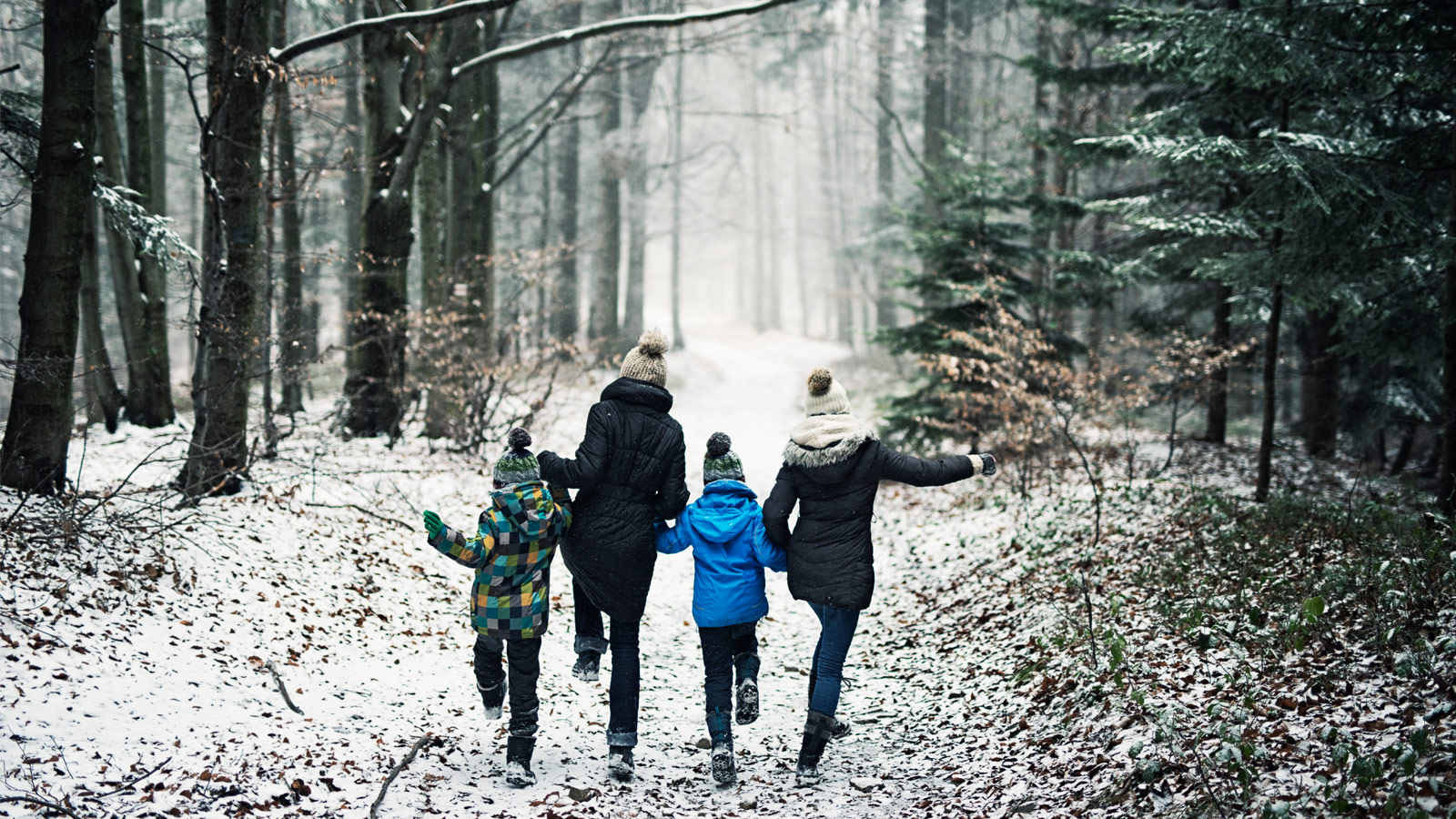 Une famille heureuse court dans une forêt hivernale