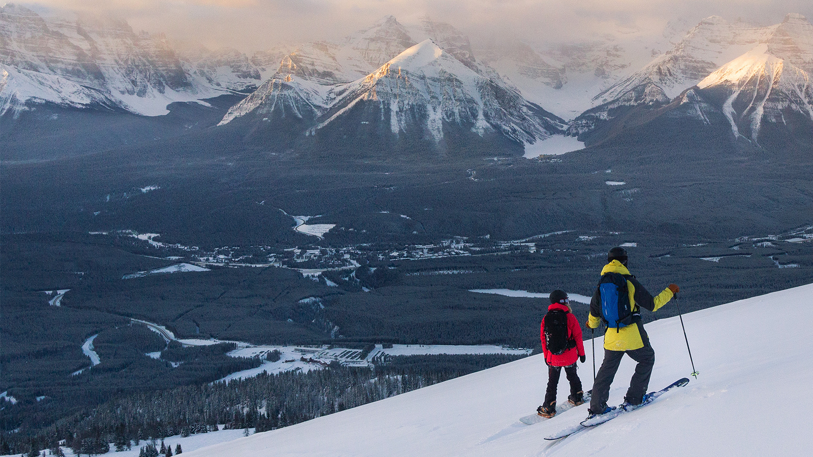 Skier and snowboarder overlooking mountains at Lake Louise