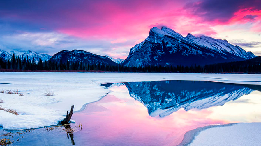 Icy mountain range overlooking water and snow