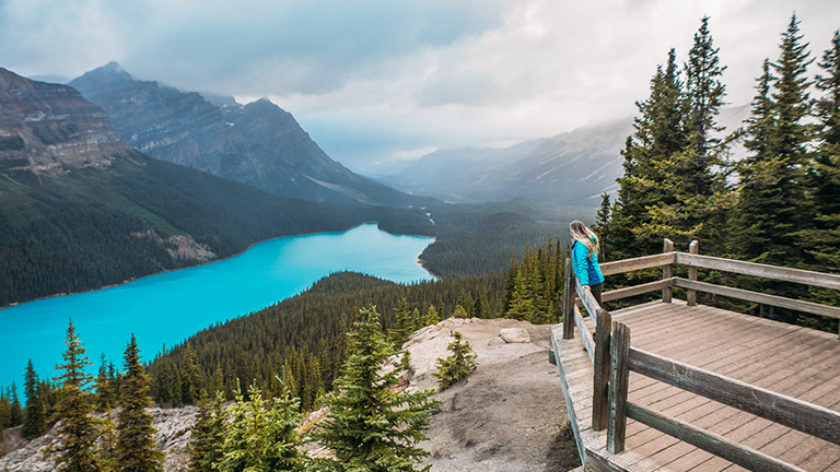 Woman on platform overlooking glacial lake and mountains