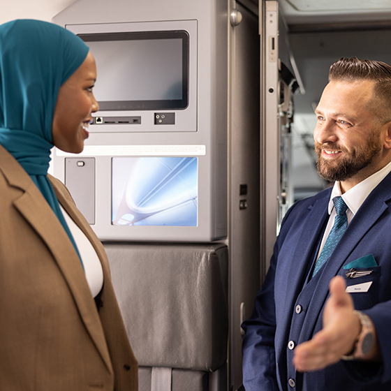 WestJet flight attendant greeting guest in aircraft