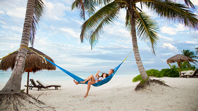 Couple lounging in hammock on beach in Mexico