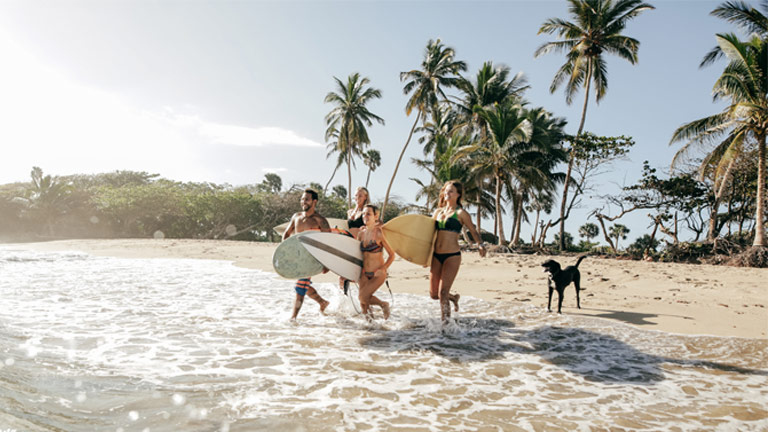 Friends running towards ocean with surfboards