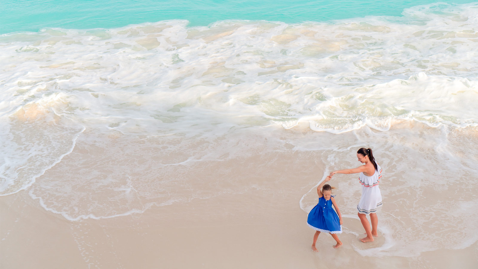 Mother and daughter dancing on the beach in the Caribbean