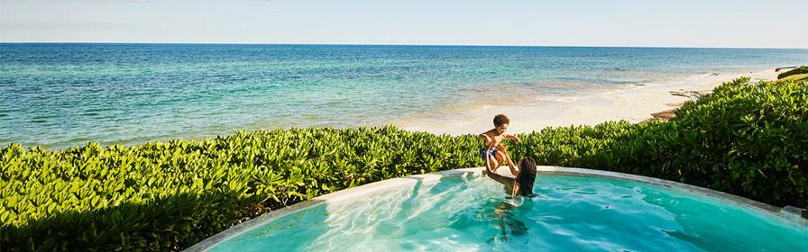 Parent and child playing in pool overlooking ocean