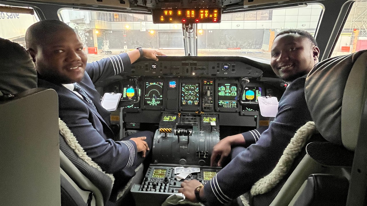 Two black male WestJet pilots on flight deck of Encore Q400